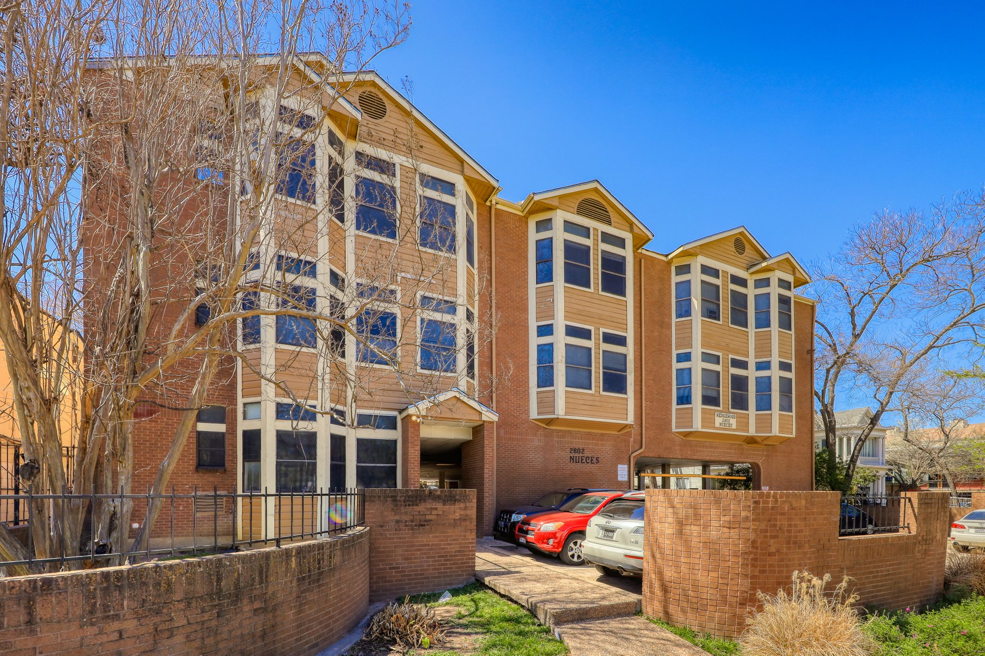 2802 Nueces Street, Unit 306 Austin, TX 78705 - Photo 20 of 20 Multi-story brick and siding structure featuring multiple bay windows, a prominent entryway, and visible parking