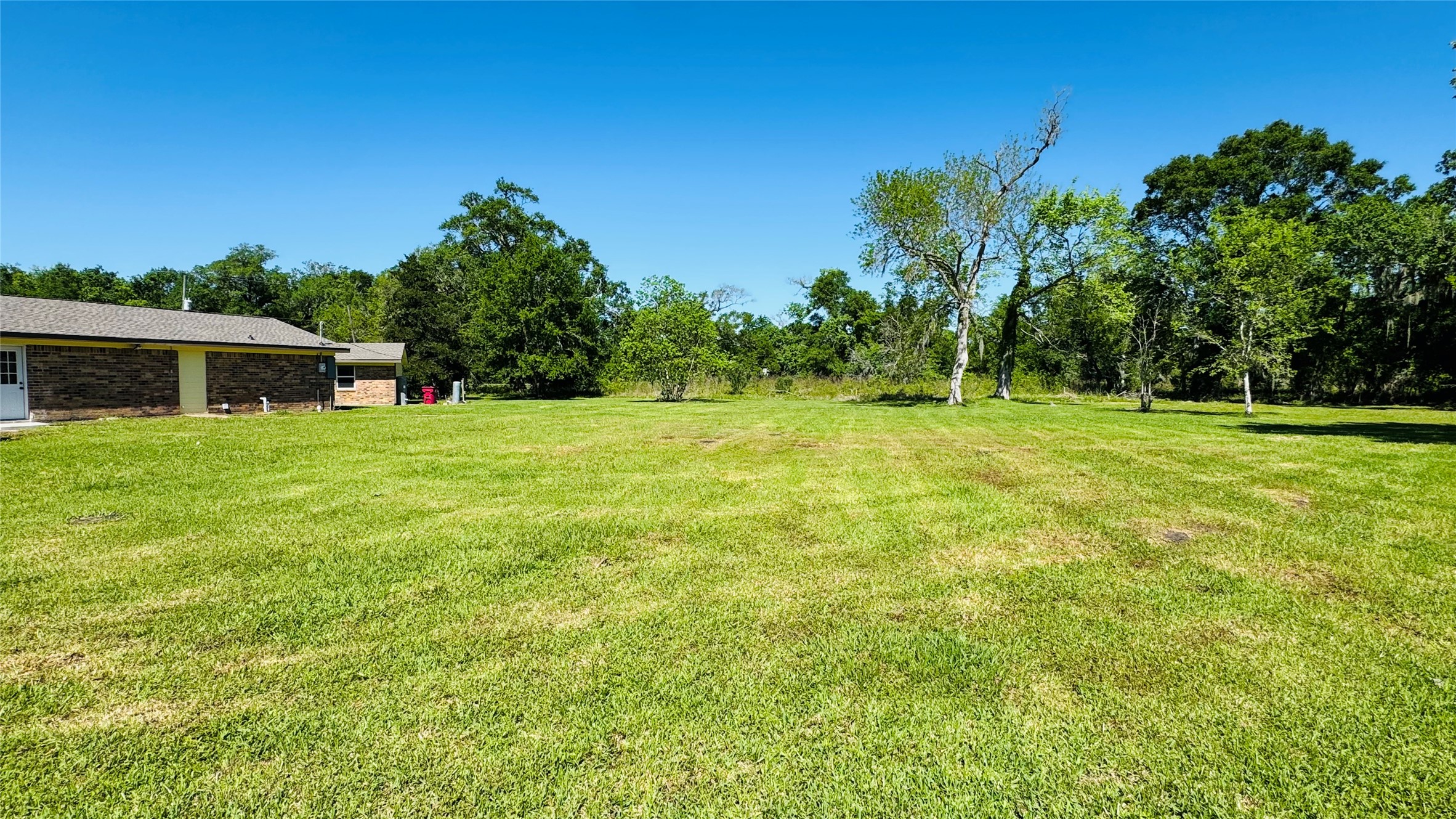 1434 County Road 878A Sweeny, TX 77480 - Photo 6 of 36 a view of a grassy field with trees in the background