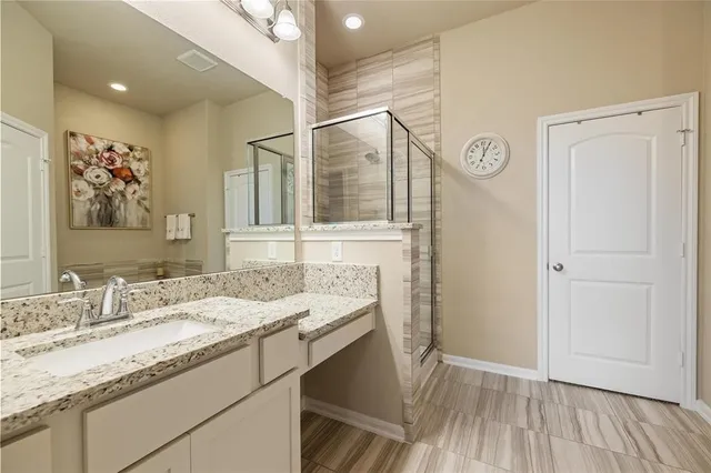 a bathroom with a granite countertop sink a mirror and a shower