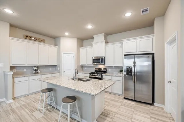 a kitchen with stainless steel appliances granite countertop a sink a stove a refrigerator cabinets and chairs