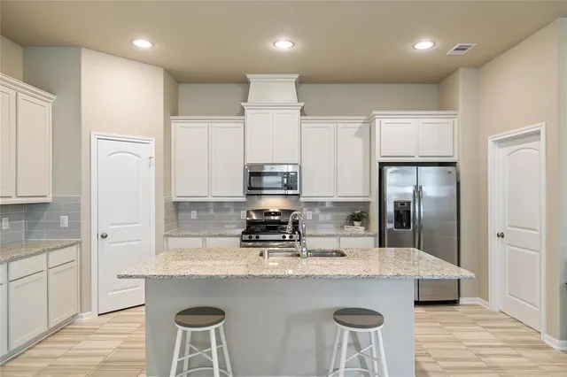a kitchen with kitchen island granite countertop a sink and refrigerator