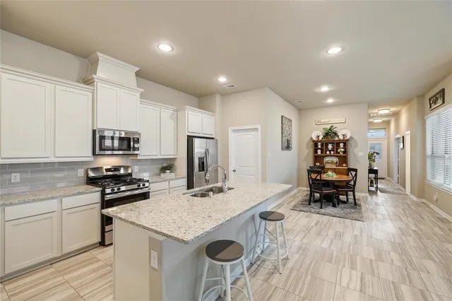 a kitchen with stainless steel appliances granite countertop a refrigerator and a stove top oven