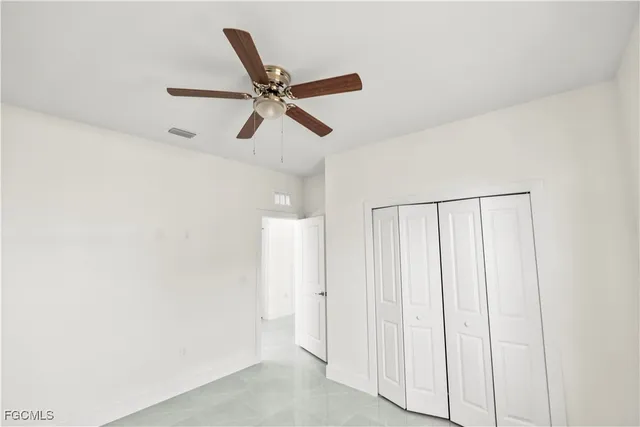 an empty room with a window and a ceiling fan