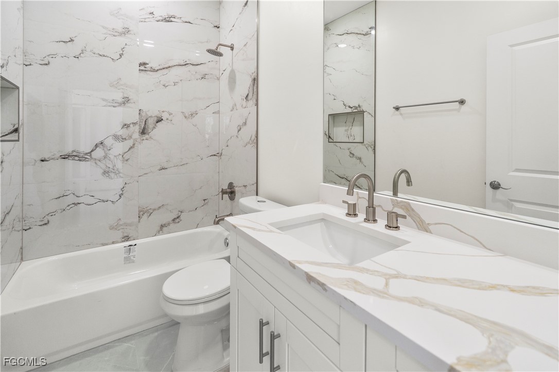 4545-4547 28th Street Southwest Lehigh Acres, FL 33973 - Photo 32 of 38 a bathroom with a granite countertop sink a toilet and shower