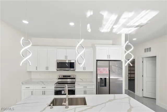 a kitchen with stainless steel appliances granite countertop white cabinets and a stove