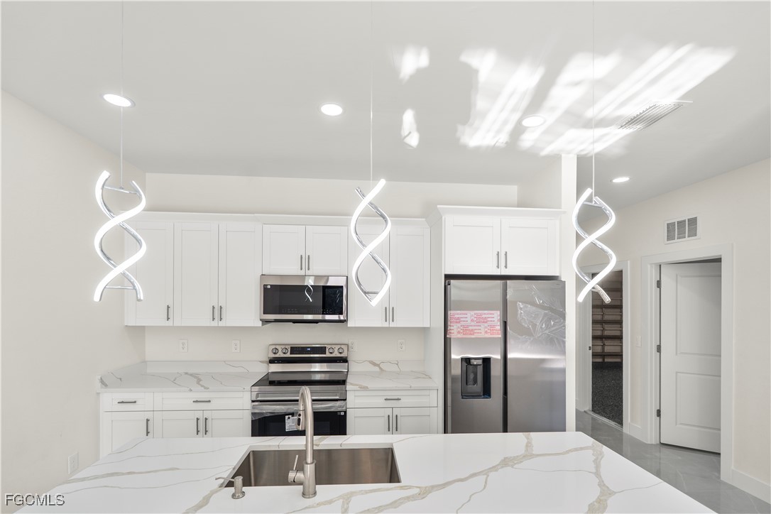 4545-4547 28th Street Southwest Lehigh Acres, FL 33973 - Photo 10 of 38 a kitchen with granite countertop a refrigerator and a stove top oven