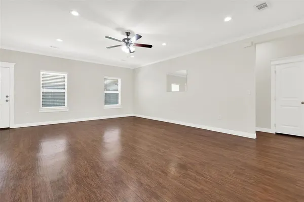 a view of an empty room with wooden floor and a window