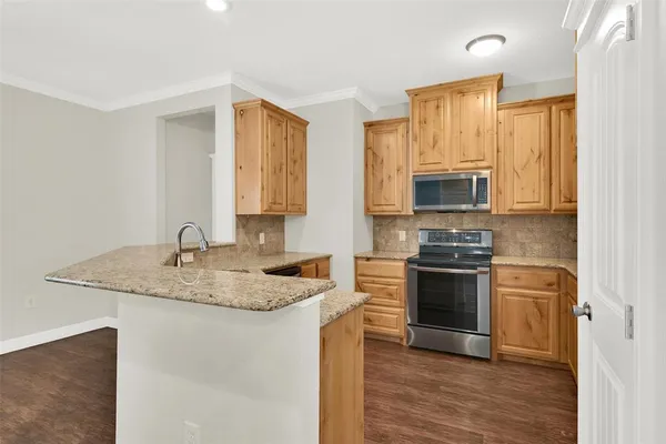 a kitchen with stainless steel appliances granite countertop a stove a sink and a microwave