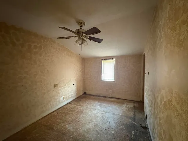 an empty room with a window and a fan