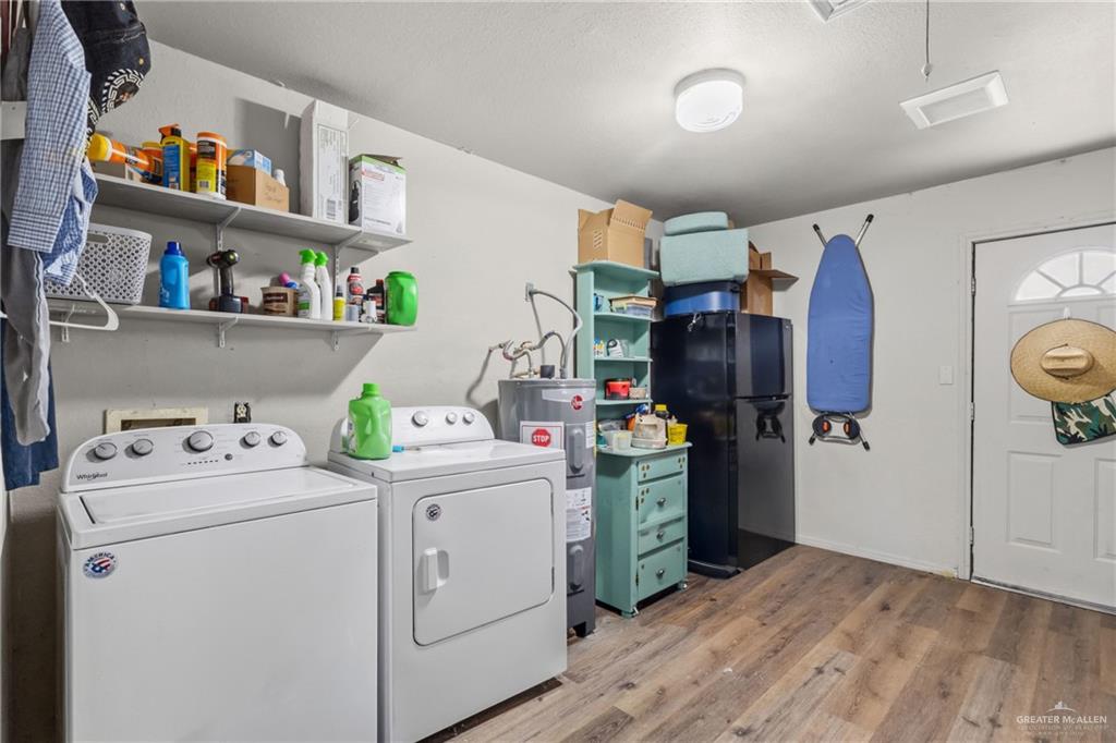 29246 26th Road San Benito, TX 78586 - Photo 14 of 23 Laundry area with wood-finish flooring, wall-mounted shelving, and a built-in water heater