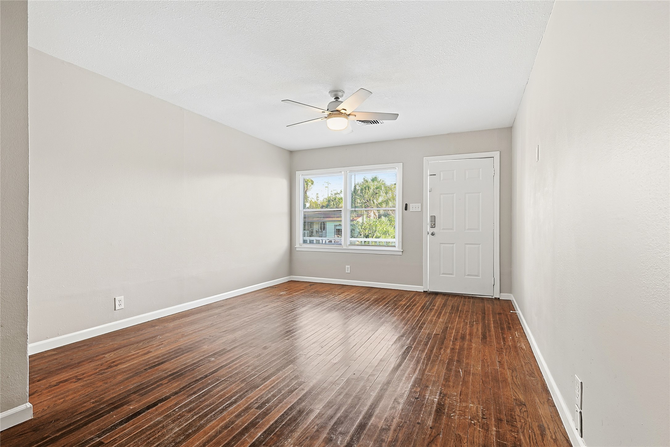 106 Trout Avenue Galveston, TX 77550 - Photo 7 of 21 an empty room with wooden floor chandelier fan and windows