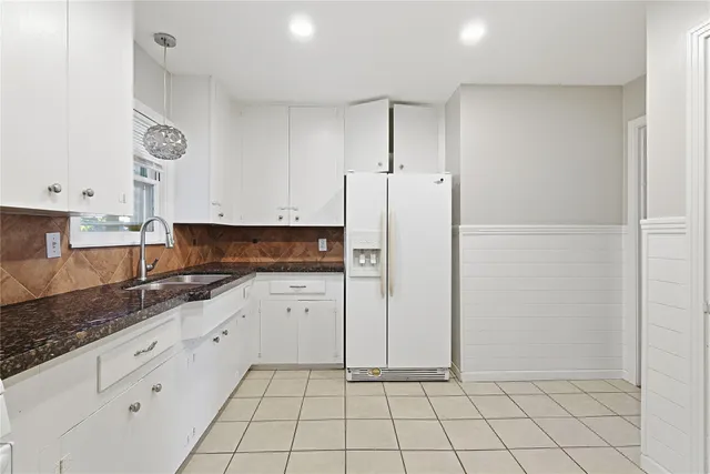 a kitchen with granite countertop white cabinets and stainless steel appliances