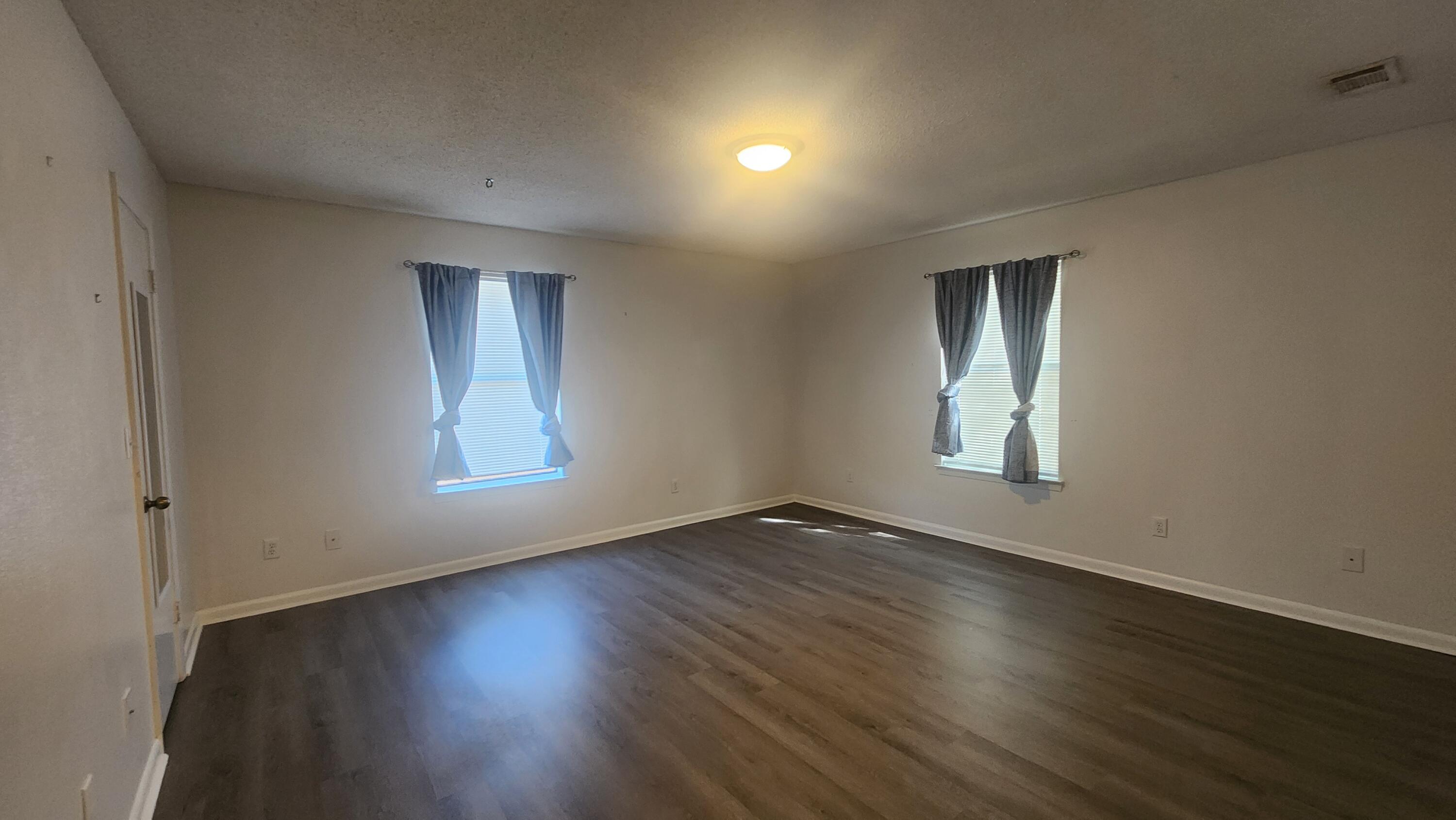 205 Marquette Avenue, Unit 1 Niceville, FL 32578 - Photo 2 of 16 an empty room with wooden floor and windows