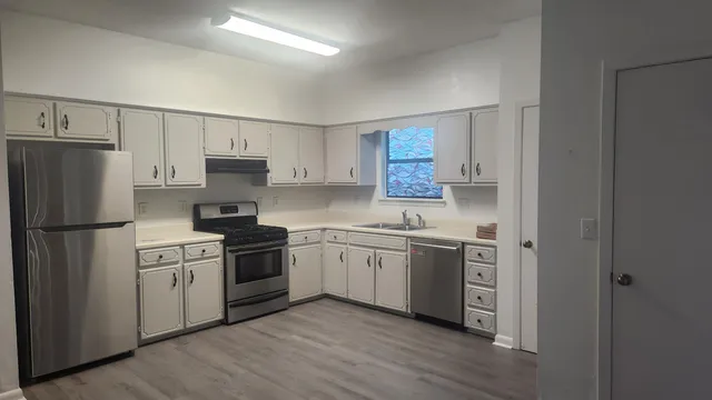 a kitchen with a white cabinets and wooden floor