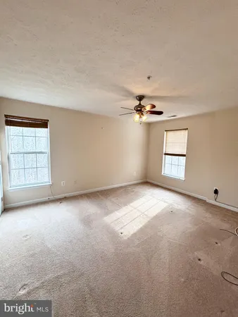 an empty room with windows and ceiling fan