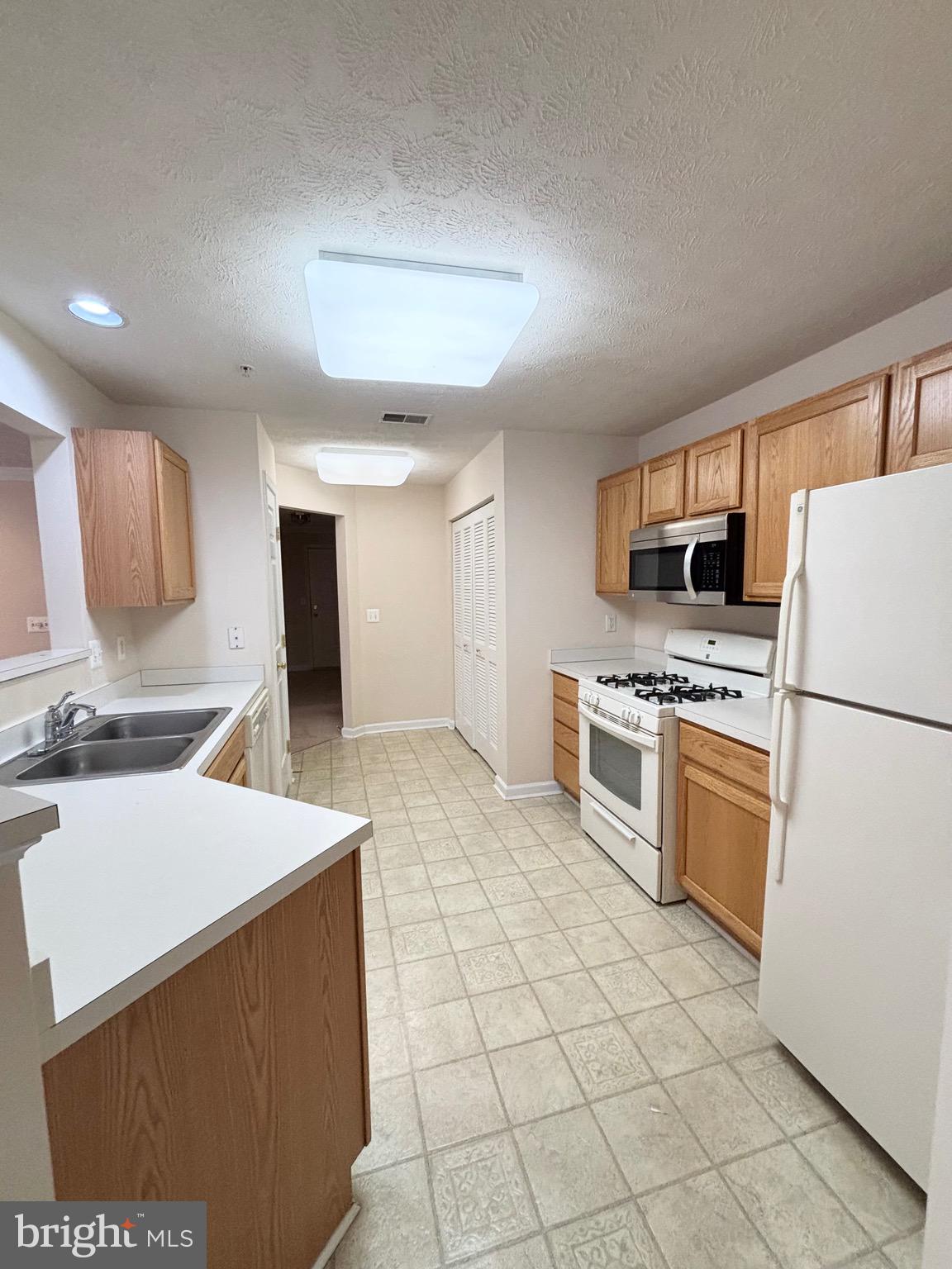 5014 Marchwood Court, Unit 7F Perry Hall, MD 21128 - Photo 14 of 16 a kitchen with a stove a sink and a refrigerator