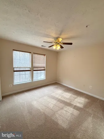 an empty room with windows and chandelier fan