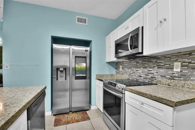 a kitchen with stainless steel appliances granite countertop a stove microwave and refrigerator