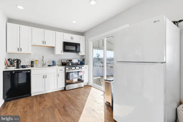 a kitchen with a refrigerator a stove top oven and white cabinets