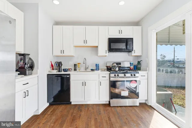 a kitchen with stainless steel appliances a white cabinets and a wooden floor