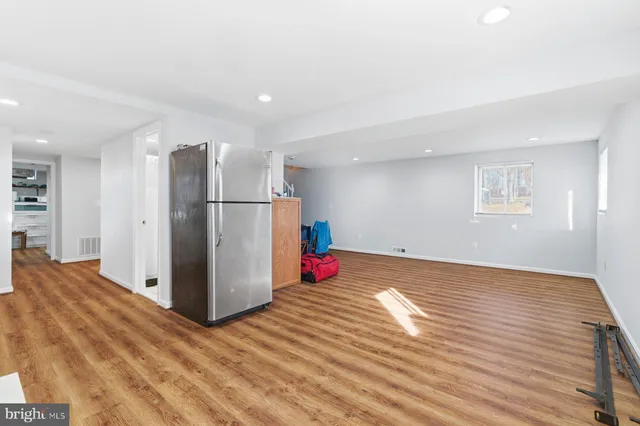 a view of kitchen and empty room with wooden floor