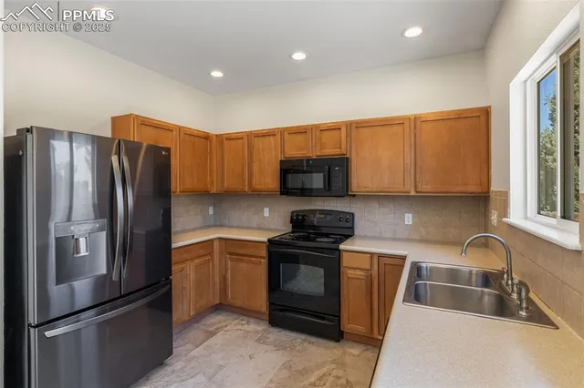 a kitchen with stainless steel appliances granite countertop a refrigerator stove and sink