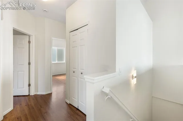 a view of an empty room with wooden floor and a bathroom