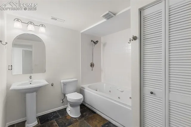 a bathroom with a bathtub shower sink mirror and toilet