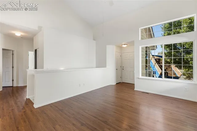 an empty room with wooden floor and windows