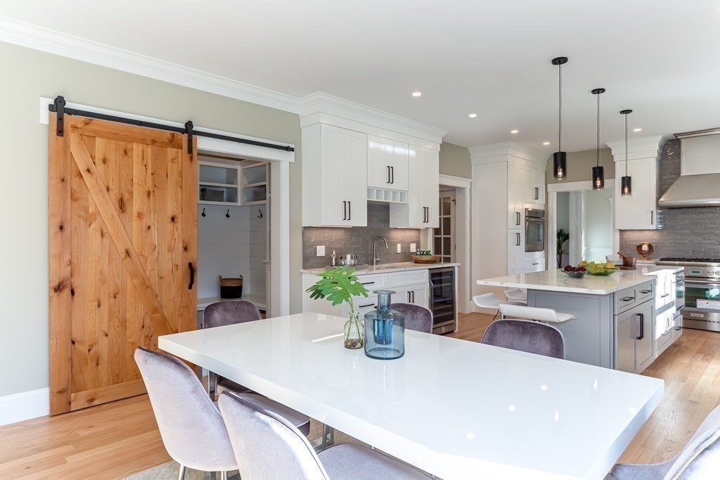 4 Whitcomb Street Natick, MA 01760 - Photo 18 of 42 a kitchen with stainless steel appliances kitchen island granite countertop a refrigerator a stove a sink a dining table and chairs with wooden floor