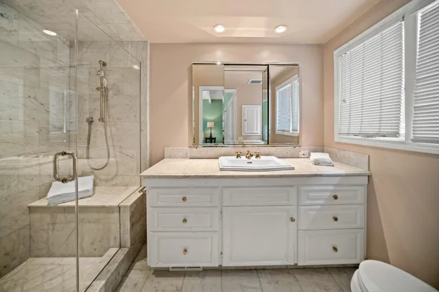 a bathroom with double vanity sink and mirror with shower