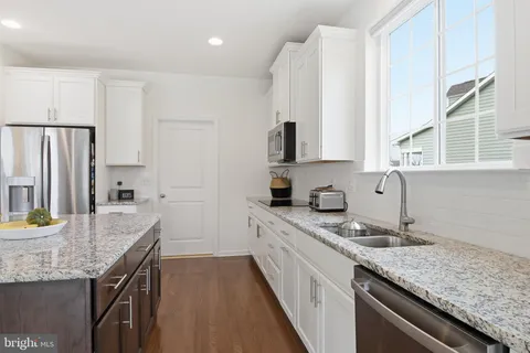 a kitchen with granite countertop a sink stove and refrigerator