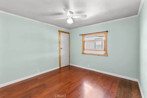 an empty room with wooden floor chandelier fan and windows