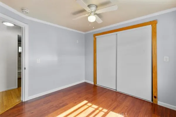 a view of empty room with wooden floor and fan