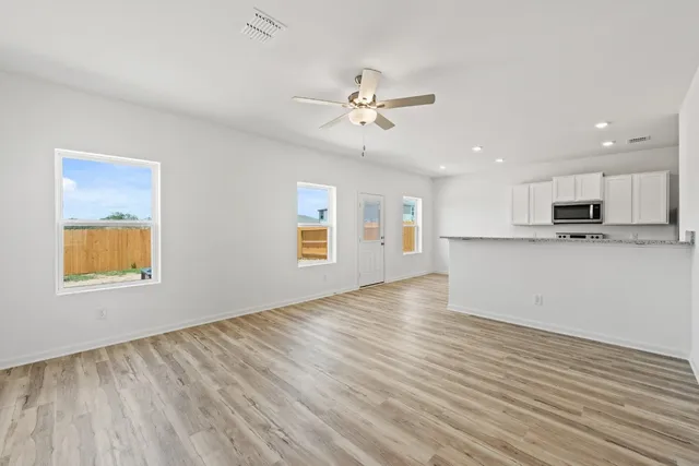 a view of an empty room with window and wooden floor