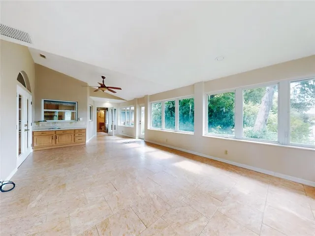 en empty room with windows and ceiling fan