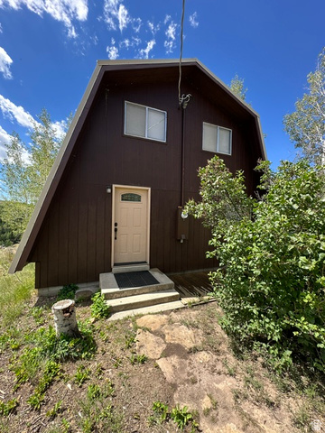 1085 West Elk Road Helper, UT 84526 - Photo 32 of 40 Brown gambrel-roof structure featuring an entry door with an arched window insert, a concrete stoop with two steps, and a dark entry mat