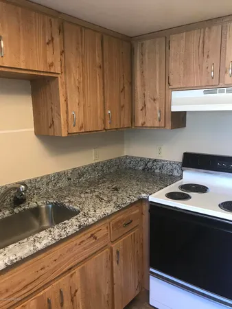 a kitchen with granite countertop cabinets sink and stove