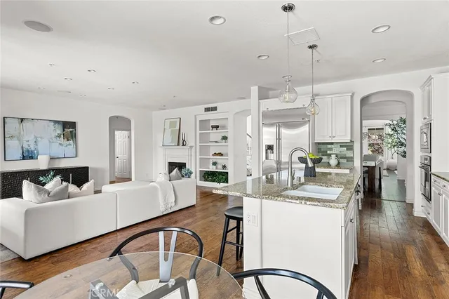a kitchen with stainless steel appliances granite countertop a table chairs sink and cabinets