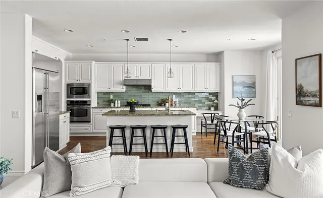 a kitchen with stainless steel appliances granite countertop a table chairs in it and white cabinets
