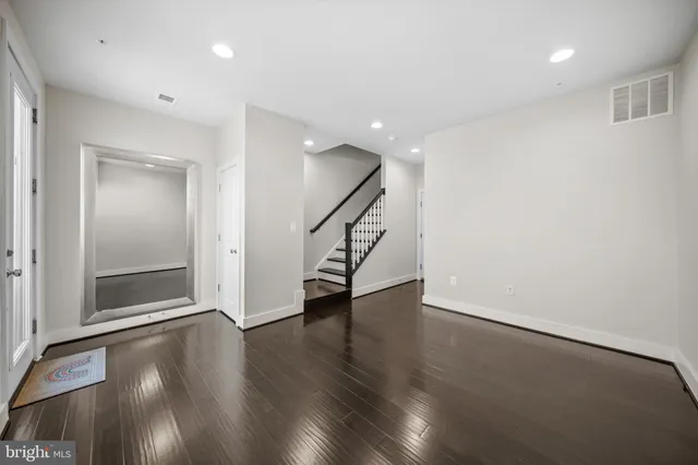 a view of an empty room with wooden floor and stairs