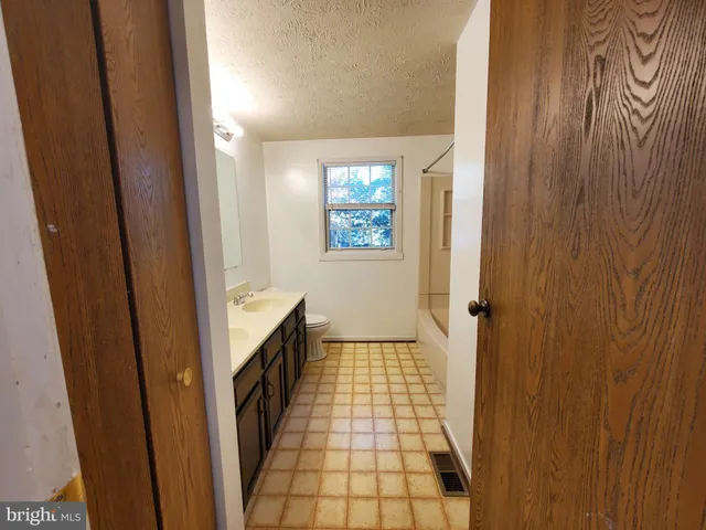 a bathroom with a sink a toilet a window and a mirror