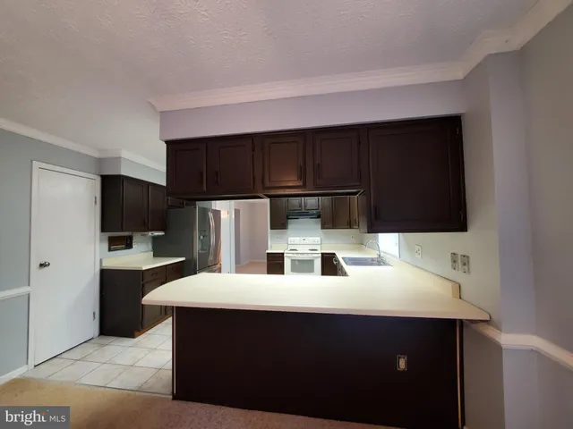 a kitchen with stainless steel appliances a sink a microwave a refrigerator and cabinets
