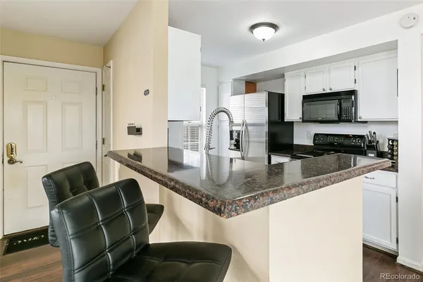 a kitchen with stainless steel appliances granite countertop a stove top oven a sink a dining table and chairs