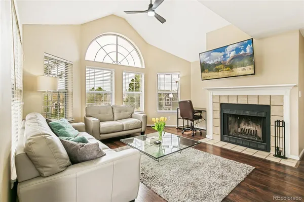 a living room with furniture a rug a fireplace and a large window