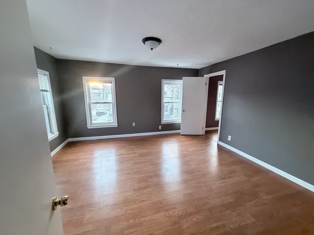 an empty room with wooden floor and windows