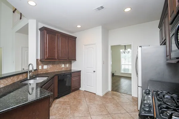 a kitchen with stainless steel appliances granite countertop a sink and a refrigerator