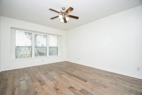 an empty room with wooden floor and windows