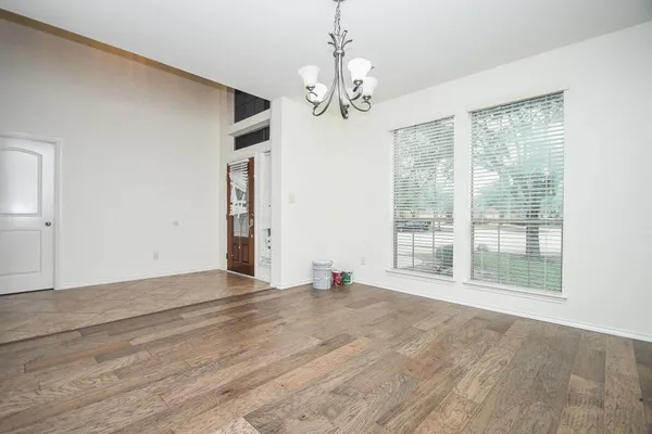 a view of an empty room with a window and wooden floor