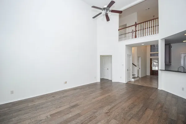 a view of a hallway with wooden floor and a ceiling fan